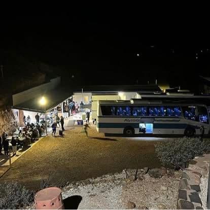 A tour-group bus parked at a lit Chef Skills serving area at night.