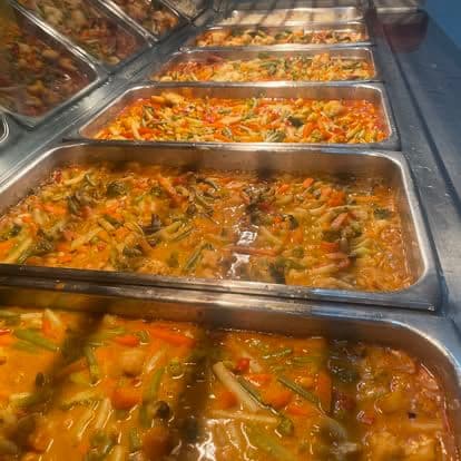 Chef Skills team preparing buffet-style meals in bain-marie trays at a camp.