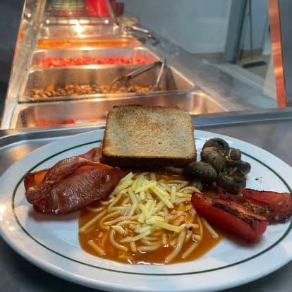 A cooked Chef Skills breakfast plate with bacon, mushrooms, hash browns and toast.